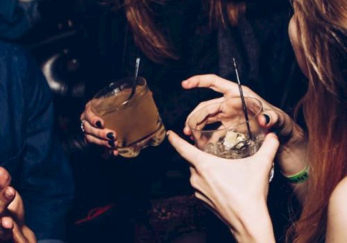 People enjoying drinks together, with visible laughter and relaxed gestures, suggesting a social gathering or party setting.