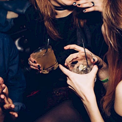 People enjoying drinks together, with visible laughter and relaxed gestures, suggesting a social gathering or party setting.